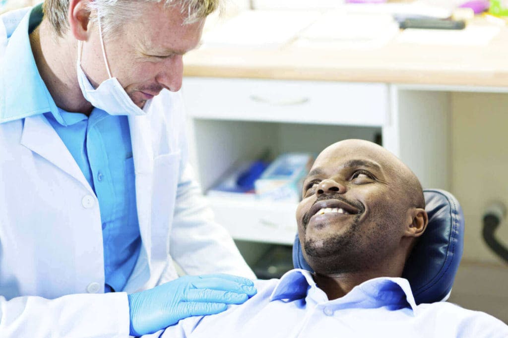 smiling dentist talking to a smiling patient in dentist chair