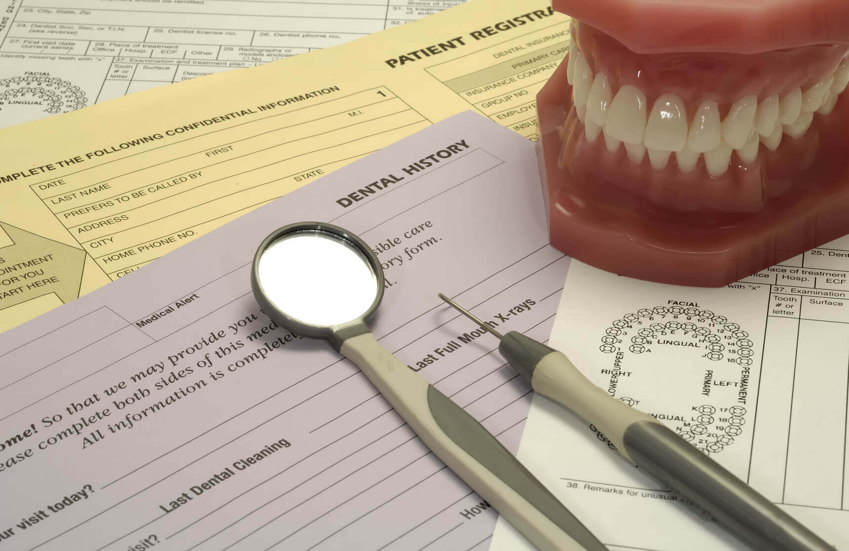 calgary dental benefits with dental instruments and mouth display model on paperwork