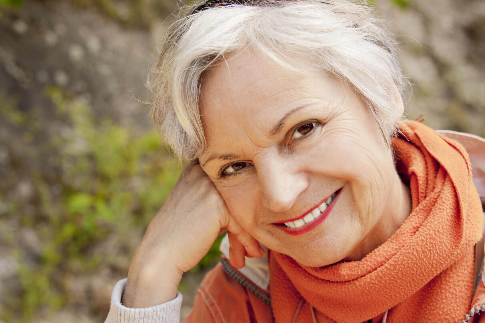 happy senior woman smiling outdoor with white teeth wearing orange scarf