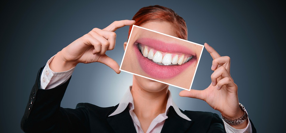 person holding up a photo of smiling mouth with white teeth in front of their face