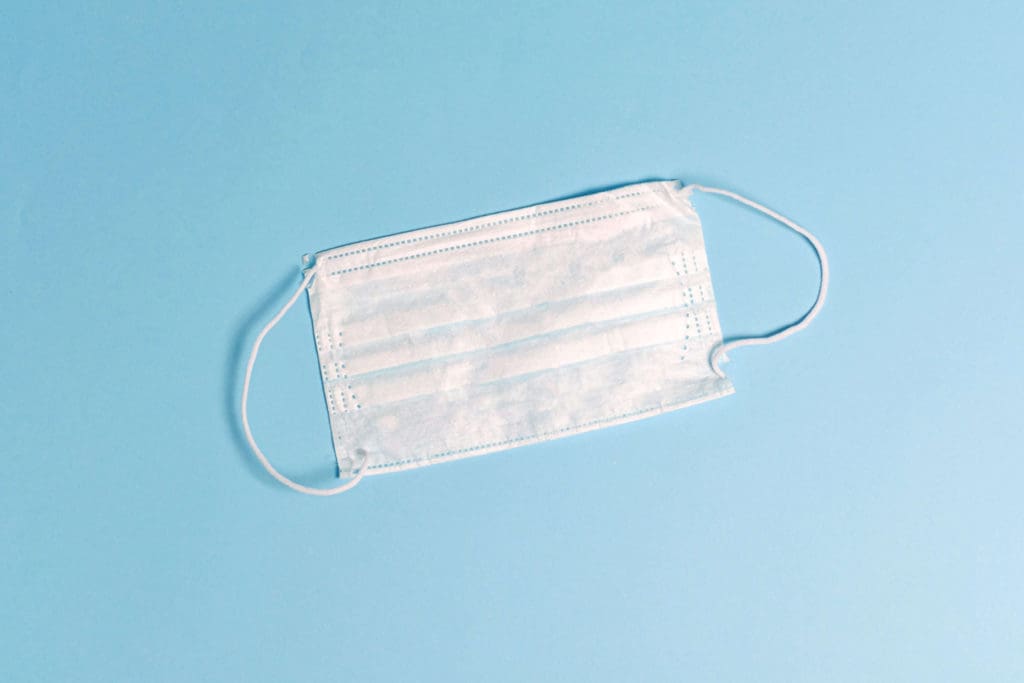 a white face mask against a blue background for covid update