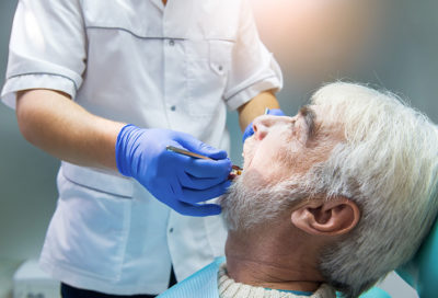 A dentist working with a senior dental patient.