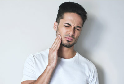 A man holds his face, indicating a toothache.