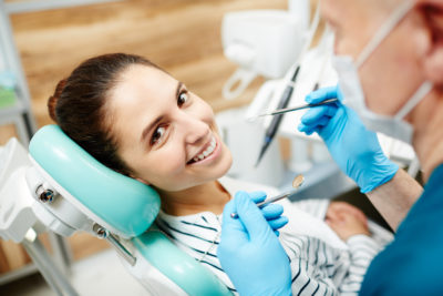 Smiling patient of dentist looking at camera during oral check-up