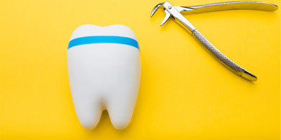 a 3D tooth sits beside a dental extraction tool on a yellow background