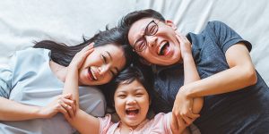 A family laying on the ground with their hands in their ears.